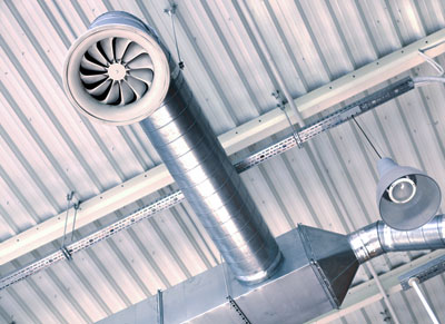 An image showing commercial ventilation pipes on a ceiling in a commercial space.